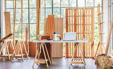 Woodworking workbench with tools and equipments electric drilling machine, paper blueprint clipboard, pencils, handsaw, hammer, loud speaker and laptop computer in housing building construction site