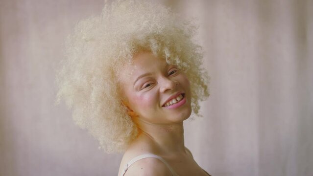 Studio shot of confident and positive young albino woman wearing underwear laughing and smiling - shot in slow motion
