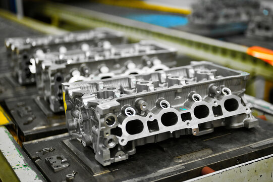 Car engine cylinder heads in housings on conveyor in shop