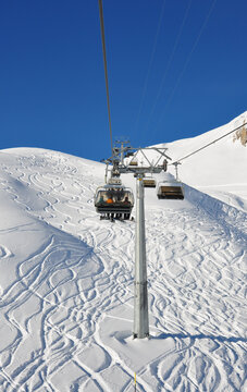 ski slope and ski lift in Switzerland, Samnaun, skiers sitting on ski lift, snowboarders ride a chairlift, ski lift picture, tracks in the snow
