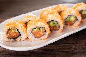 Sushi roll with salmon, reo, avocado and cucumber on a white plate. Japanese cuisine