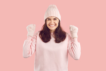 Luck, winter and people. Happy satisfied woman in pink winter mittens and hat doing winner gesture...