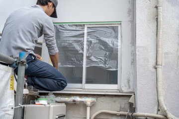 住宅の外壁の塗装　養生をする職人 - obrazy, fototapety, plakaty