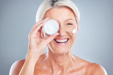 Beauty, skincare and senior woman with face cream for moisturizing on a gray studio background....