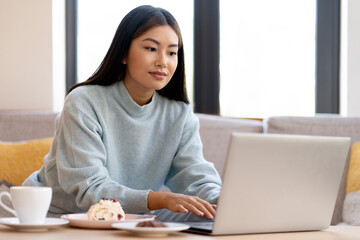 Female student using laptop computer sitting at the cafe, preparing homework
