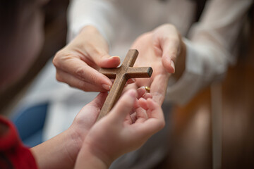 Children's hand with cross at church. Concept of hope, faith, christianity, religion, church online.
