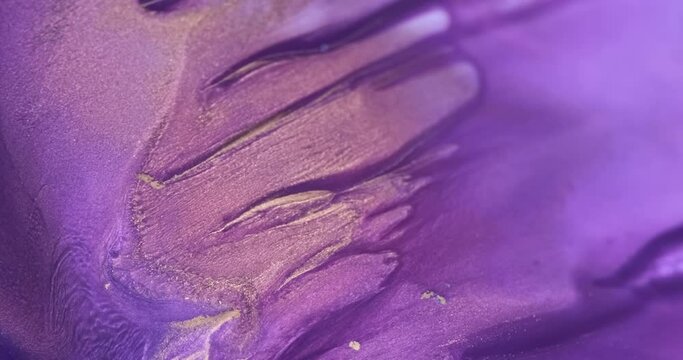 Bright purple ink flow down, close-up abstract background. Shiny vivid purple-gold paint flowing fluid art texture. 4k footage gold violet liquid abstract in motion. Golden lilac move glitter backdrop