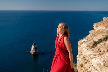 A woman in a red flying dress fluttering in the wind, against the backdrop of the sea.