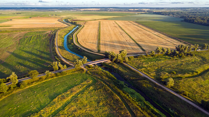 Top view of the countryside, agricultural fields, river and road bridge across the river