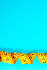 measuring tape on a blue background, copy space. The topic of weight loss, diet, proper nutrition, excess weight, tailoring. vertical snapshot.