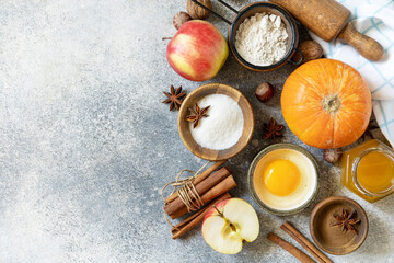 Baking food background. Pumpkins, apples, honey, nuts and seasonal spices for pumpkin or apple pie on a gray tabletop. View from above. Copy space.