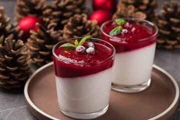 Vegan dairy free coconut Panna cotta with cranberry sauce in glasses on a dark stone table. Healthy...