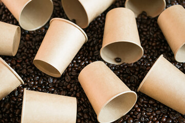 Mock up disposable coffee cups lying on coffee beans. Some empty paper coffee cups.