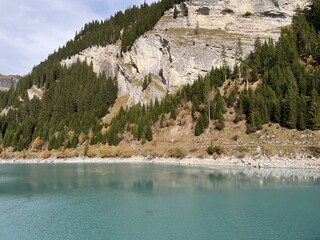 Steep stone cliffs and vertical rocks above the reservoir lake Panixersee (Lag da Pigniu) or...