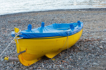 Barque jaune recouverte d'une bâche bleue sur la plage au bord de la mer méditerranée à...