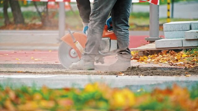 Roadworks Construction Worker Operating Tarmac Circular Saw Cutting Asphalt on Busy Street