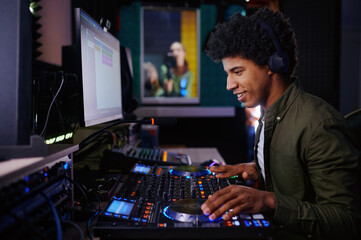 Portrait of radio host using sound mixer in studio