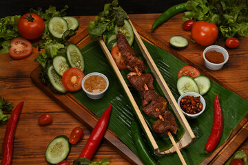 Mala is a hot and spicy and delicious street food. Delicious grilled meat on wooden board surrounded by fresh vegetable