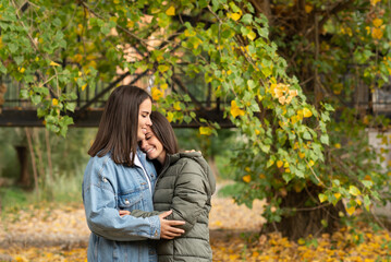 Portrait of lesbian couple embracing on a park in a nice autumn day.