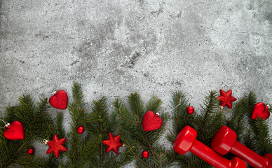 Two red dumbbells, Christmas tree branches and decorations. Healthy fitness lifestyle holiday...