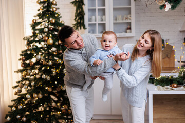 A happy family. Happy young couple with their little son in the kitchen decorated for the new year....