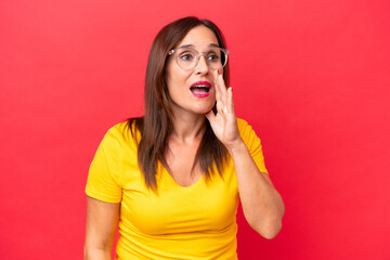 Middle-aged caucasian woman isolated on red background shouting with mouth wide open to the side