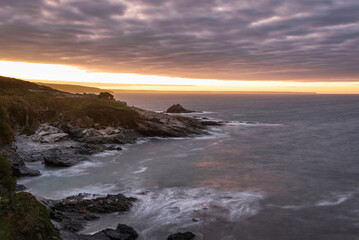 Fototapeta na wymiar Dramatic landscape sunrise image at Prussia Cove in Cornwall England with atmospheric sky and ocean