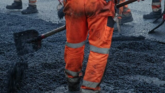 Roadwork Physical Workers in Protective Work Wear Repairing Street Tarmac Surface with Hot Asphalt