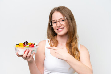 Young pretty woman holding a bowl of fruit isolated on white background and pointing it