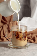 Pouring creme in a cup of coffee.