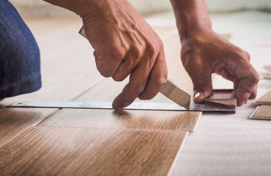 A Technician Is Cutting Luxury Vinyl Floor Tiles With A Cutter To Lay The Floor Before Placing It On The Leveling Foam.