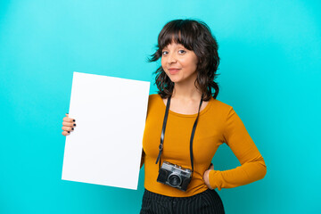 Young photographer latin woman isolated on blue background holding an empty placard with happy...