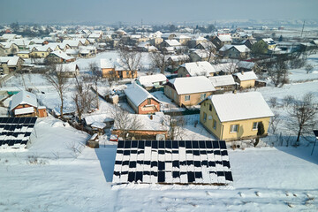 Aerial view of snow melting from covered solar photovoltaic panels installed on house rooftop for producing clean electrical energy. Low effectivity of renewable electricity in nothern region winter