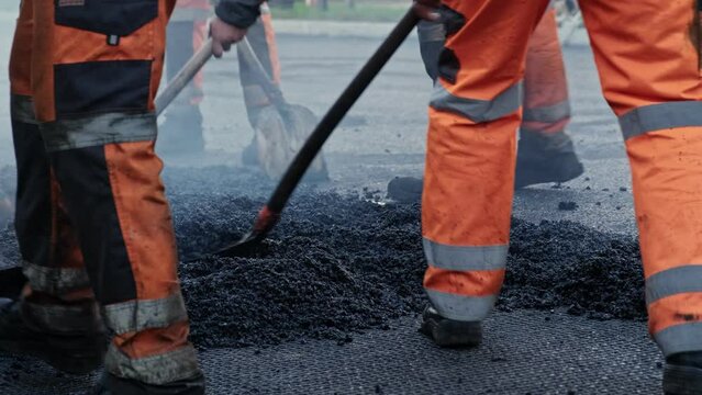 Roadwork Physical Workers in Protective Work Wear Repairing Street Tarmac Surface with Hot Asphalt