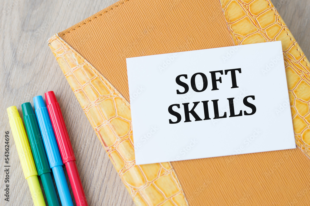 Poster a white business card with soft skills text stands on a desk against the background of an open diary