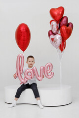 Boy with red balloons in the form of a heart in the studio.