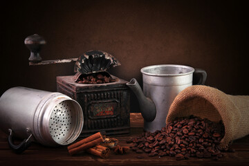 Su un tavolo in legno del caffè tostato un antico macinino ed una vecchia caffettiera - obrazy, fototapety, plakaty