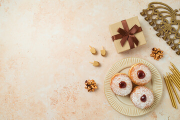 Obraz na płótnie Canvas Jewish holiday Hanukkah concept with traditional donuts, menorah and gift box on stone background. Top view, flat lay
