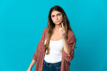 Young caucasian woman isolated on blue background frustrated and pointing to the front