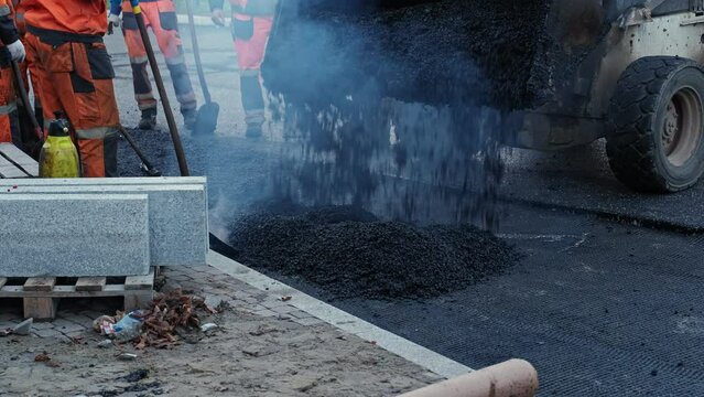 Roadwork Physical Workers in Protective Work Wear Repairing Street Tarmac Surface with Hot Asphalt