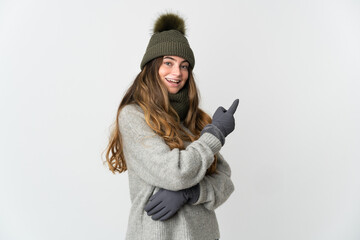 Young caucasian woman with winter hat isolated on white background pointing finger to the side