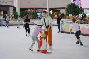Girl is learning figure skating on ice with support