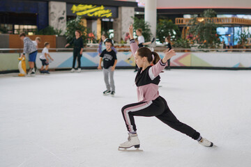 The girl is learning figure skating on ice