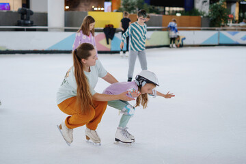 oman teaches a girl figure skating on ice.