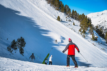 Groups of people on slope junction with focus on fast skier on steep piste in Pyrenees Mountains....