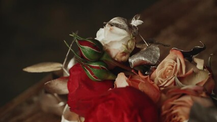 Close-up wedding flower bouquet of red florals and greenery on the wooden table, slow motion shot.