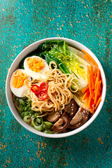 Ramen noodle soup with eggs, mushrooms, pak choi in white bowl