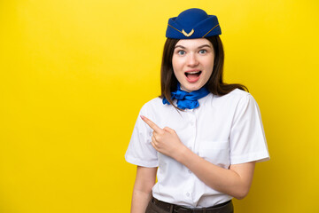 Airplane stewardess Russian woman isolated on yellow background surprised and pointing side