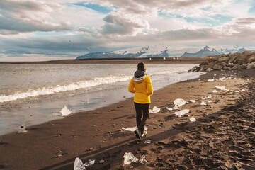 Young asian woman walking on Diamond beach with iceberg melting in summer at Iceland
