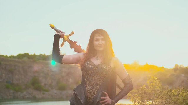 Fantasy woman viking princess warrior. Warlike girl strong face fashion model. nordic style sexy goddess holding sword in hand, red hair fly in wind. Leather costume armor. sunset sky nature summer
